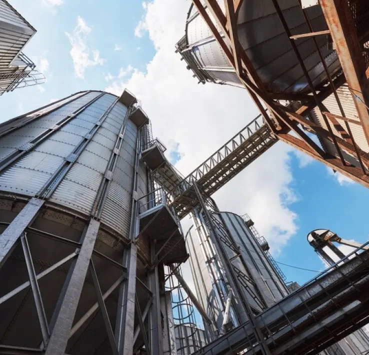 Getreidesilos und Förderbrücken, von unten vor Himmel mit Wolken fotografiert